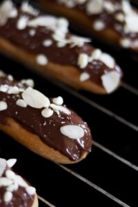 Delicious chocolate eclairs topped with almond flakes, perfect for dessert lovers.