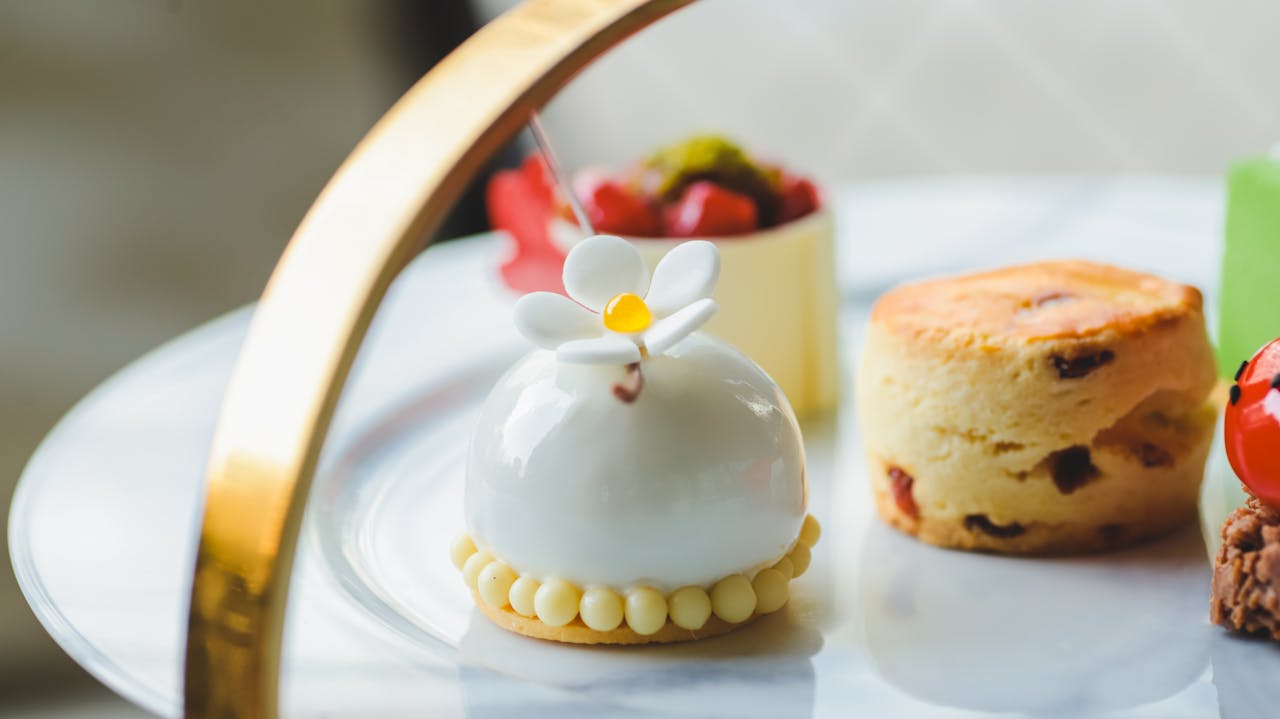 Sophisticated dessert arrangement featuring a floral-topped confection on a marble plate.